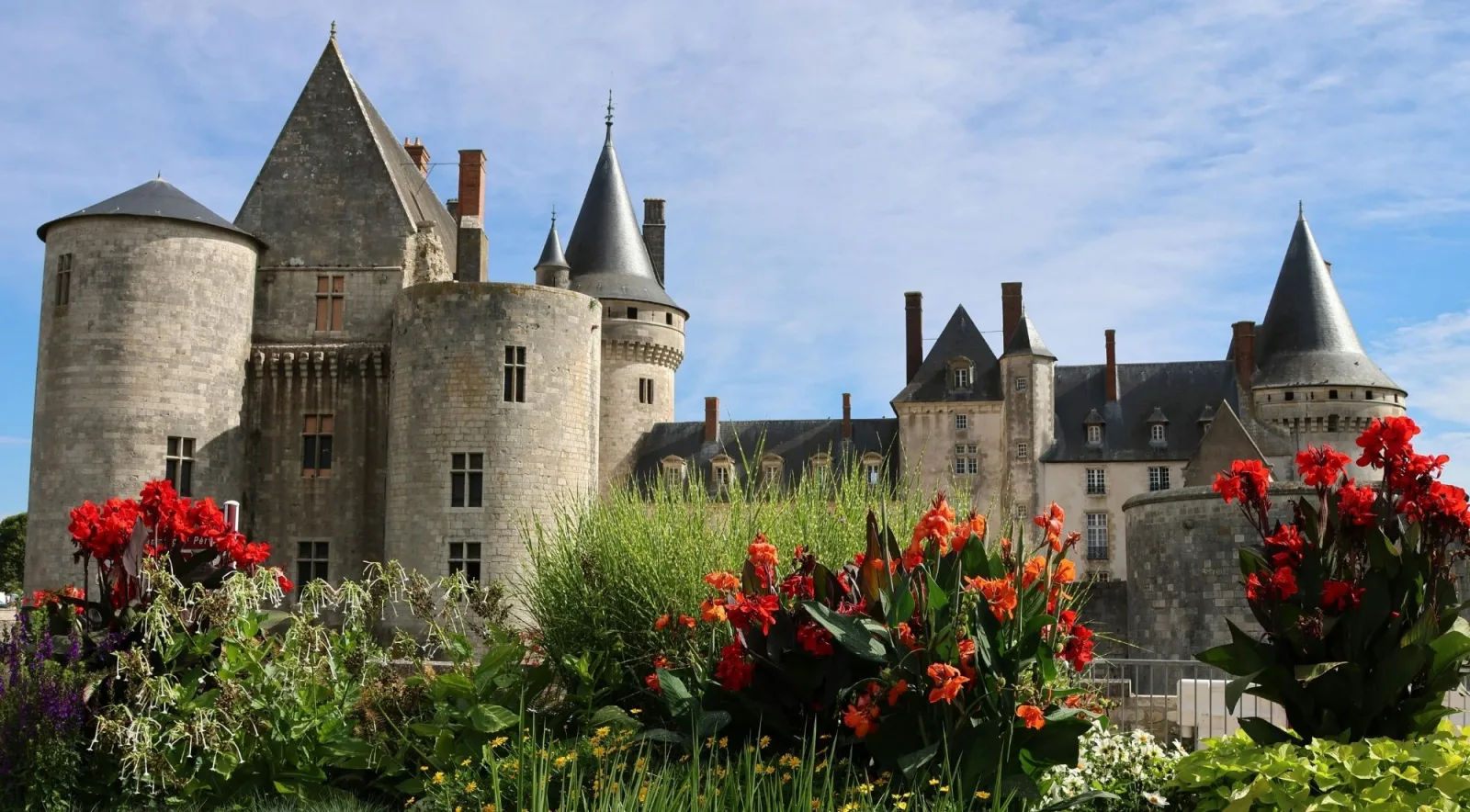 Château de Sully-sur-Loire behind summer flowerbeds, its conical towers above the moat