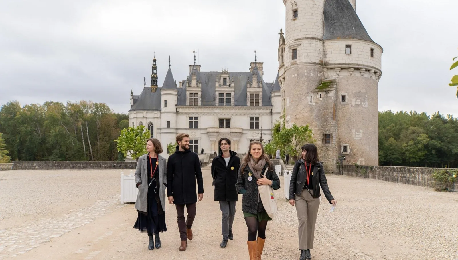 A small group walking together on the gravel forecourt at Chenonceau