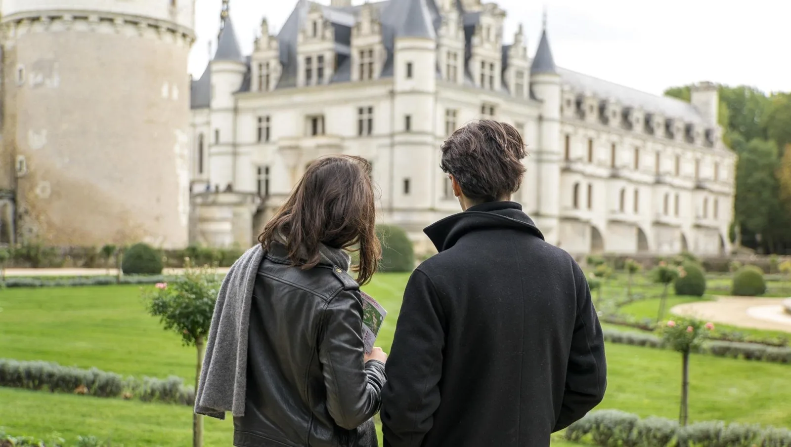 Two travellers looking across Chenonceau's garden towards the château