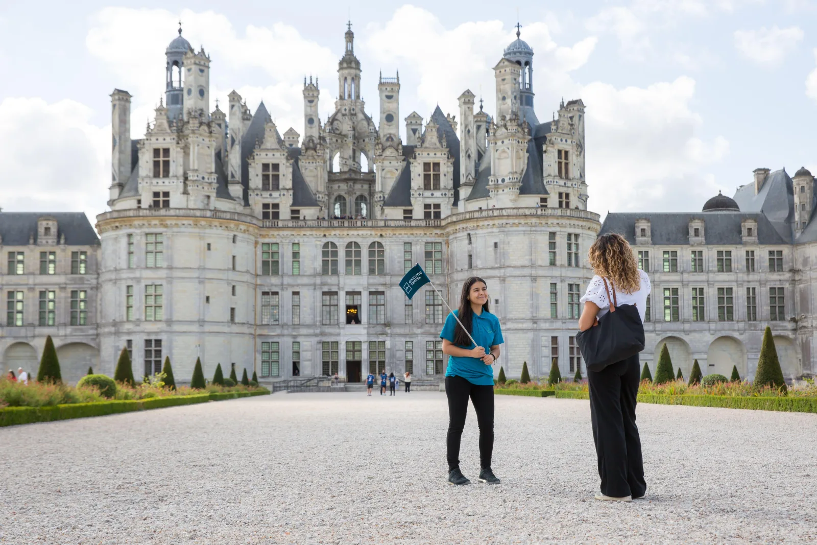 Two travellers talking on the forecourt below Chambord's north façade