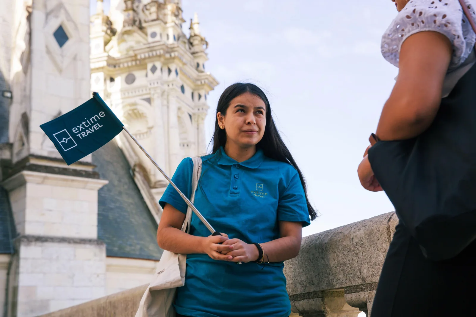 A tour guide holding the group flag beneath Chambord's carved stonework
