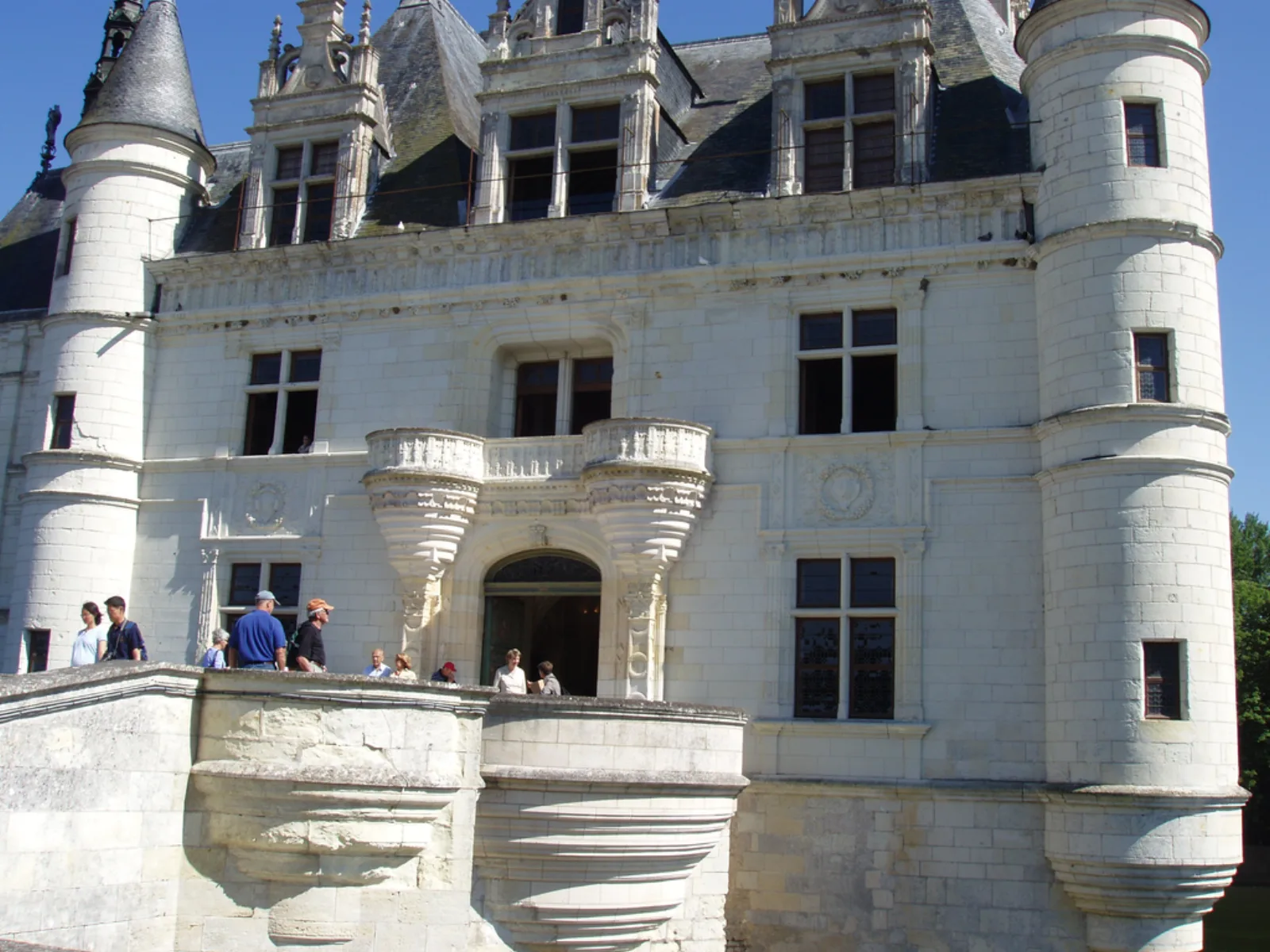 Visitors on the stone terrace beneath Chenonceau's carved entrance front