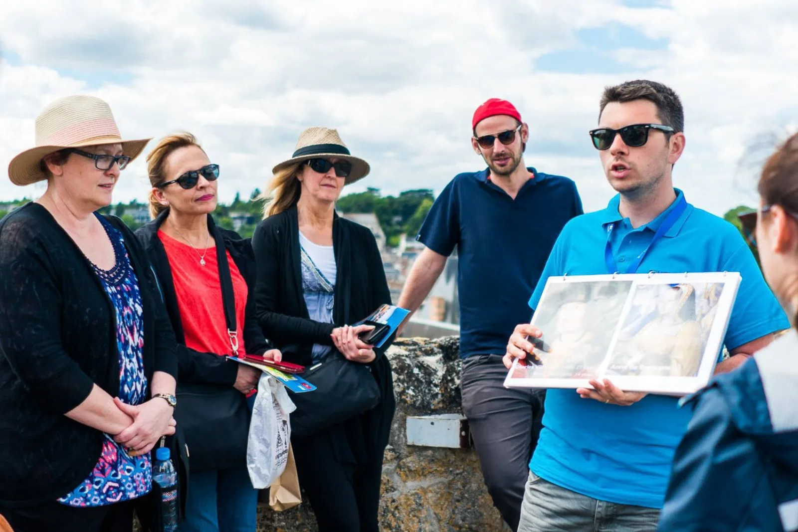 A guide showing historic prints to a small group on the Chenonceau terrace