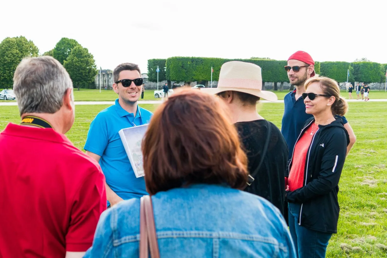 A small group listening to their guide on the lawn in the Chambord park