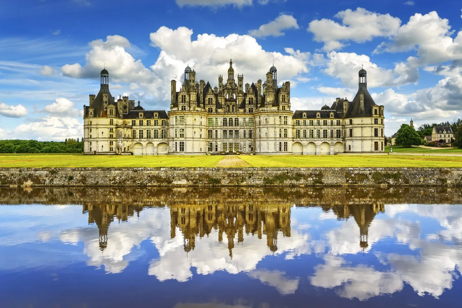 Château de Chambord reflected in still water under a bright sky