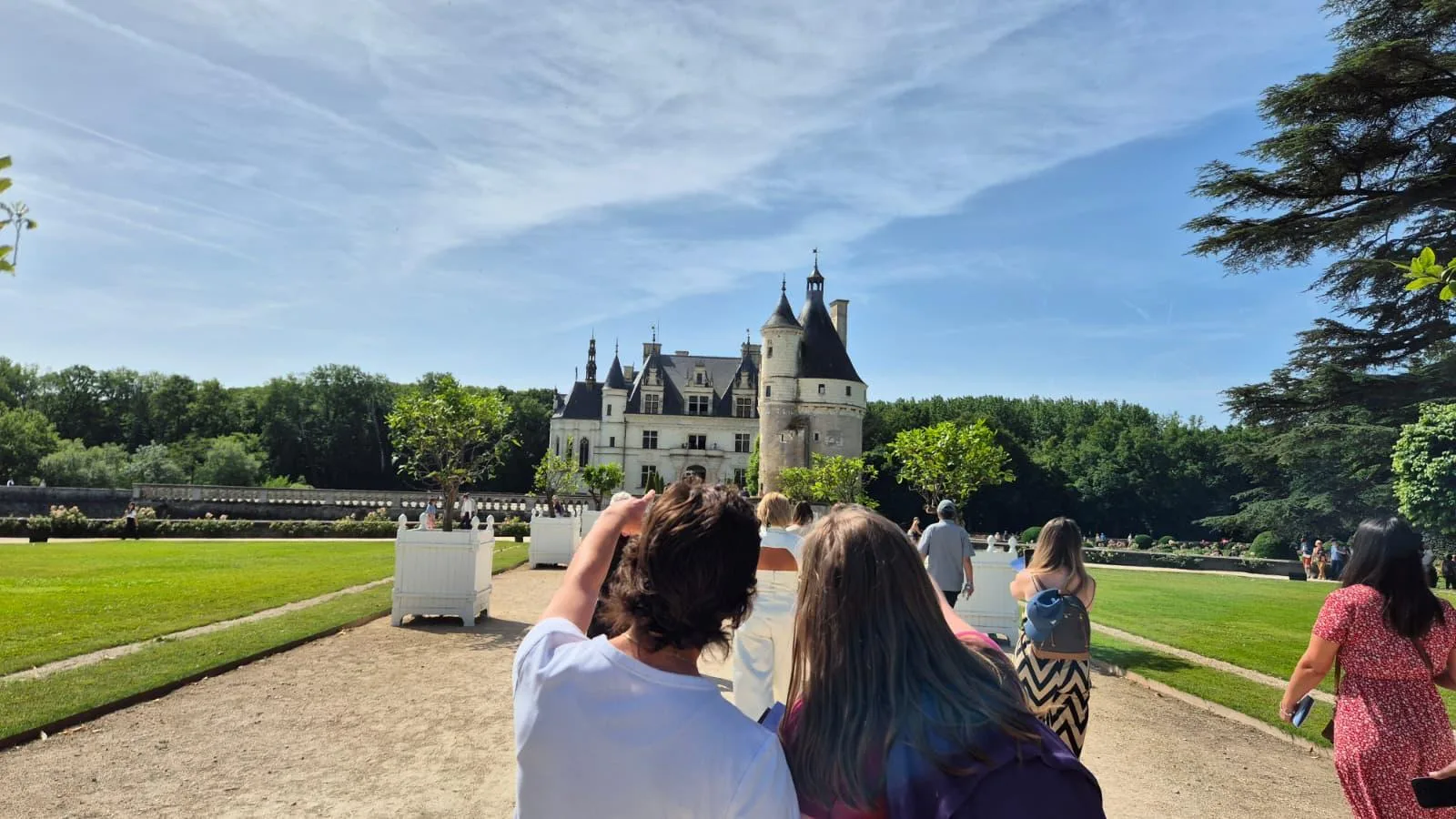 Travellers walking Chenonceau's garden parterres towards the château